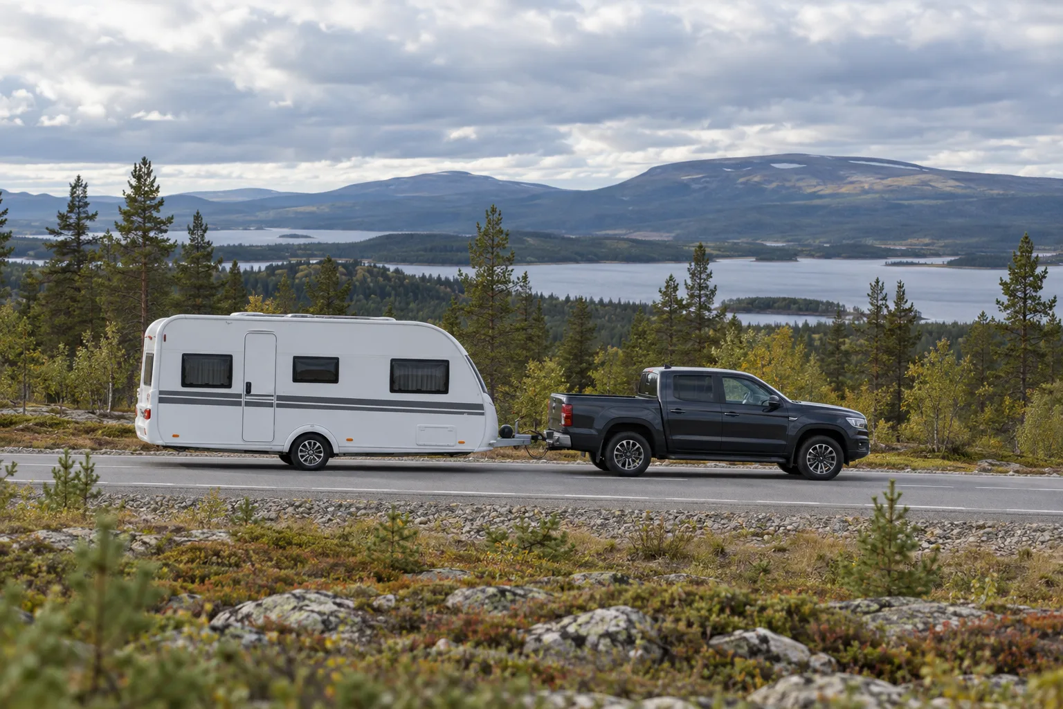 Husvagn dragen av en bil genom ett öppet norrländskt landskap
